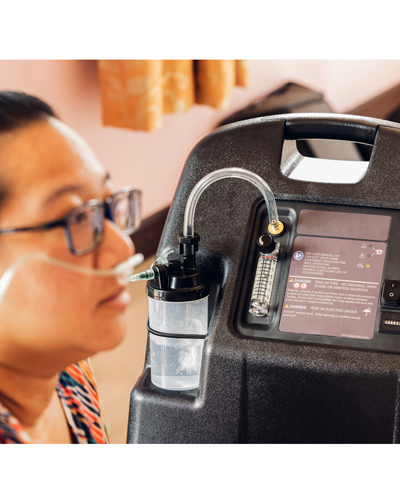 Home oxygen concentrator, patient with a cannula receiving oxygen through the nose.